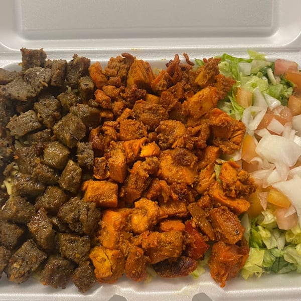 A takeout container filled with grilled chicken, beef, and a fresh salad from Philly Halal Kitchen.